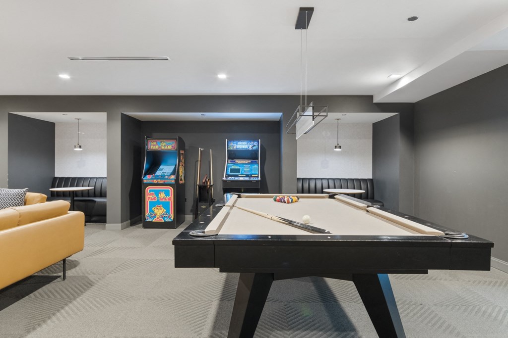 a games room with a pool table and arcade games