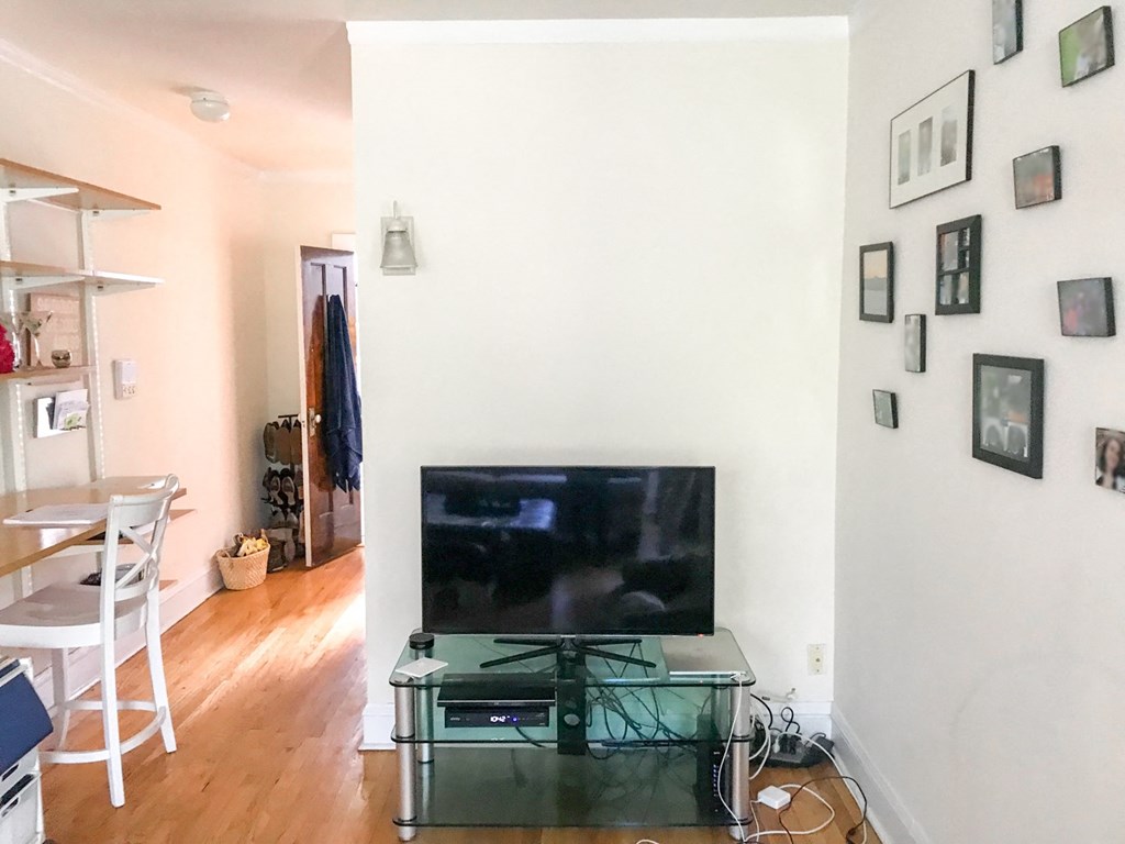 A living room with a flat screen TV and a glass coffee table.
