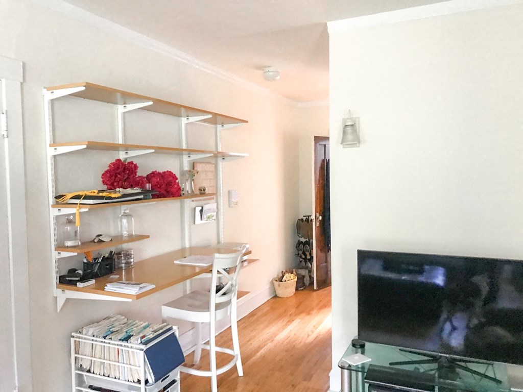 A white chair is in front of a desk with a computer on it.