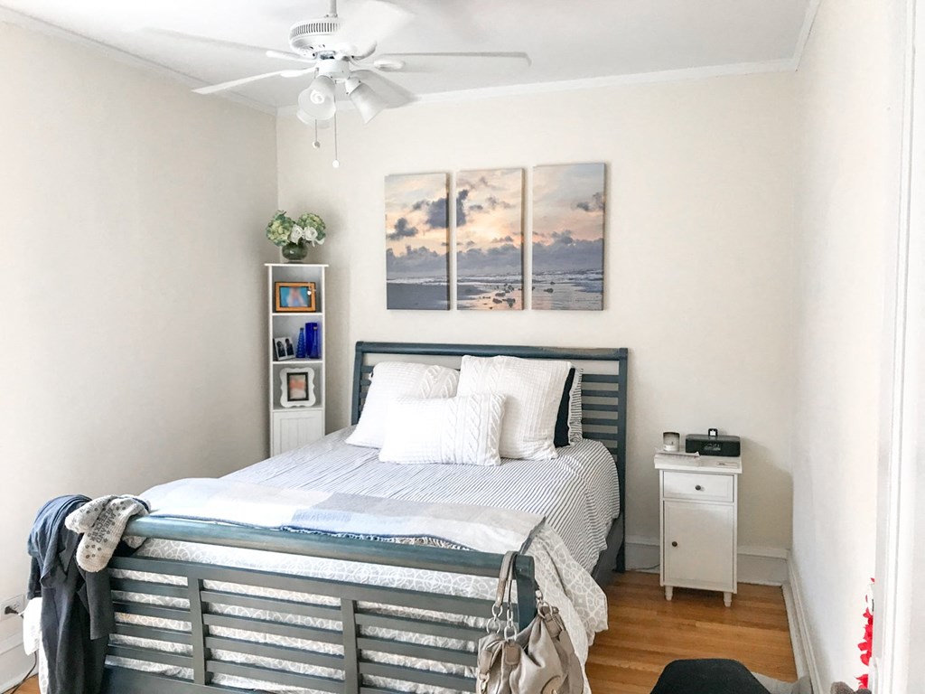 A bedroom with a bed, nightstand, and a painting on the wall.