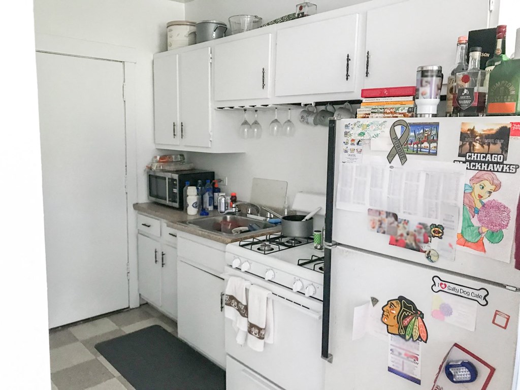 A kitchen with white appliances and a refrigerator covered in magnets and decorations.