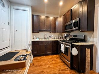 a kitchen with dark cabinets and a wooden floor