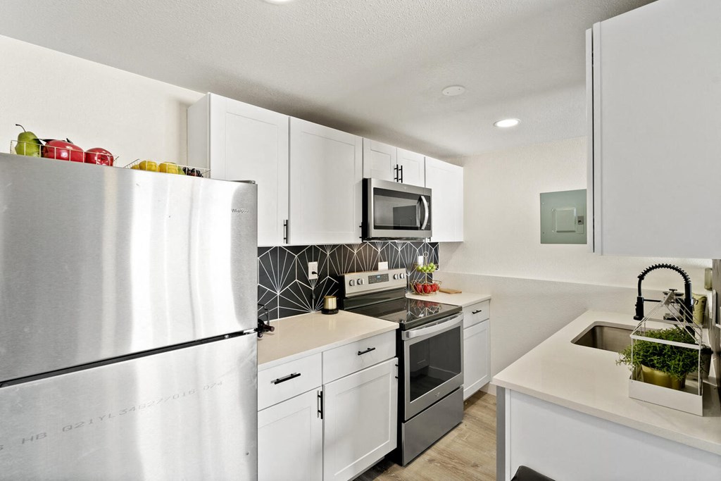 a kitchen with white cabinets and stainless steel appliances