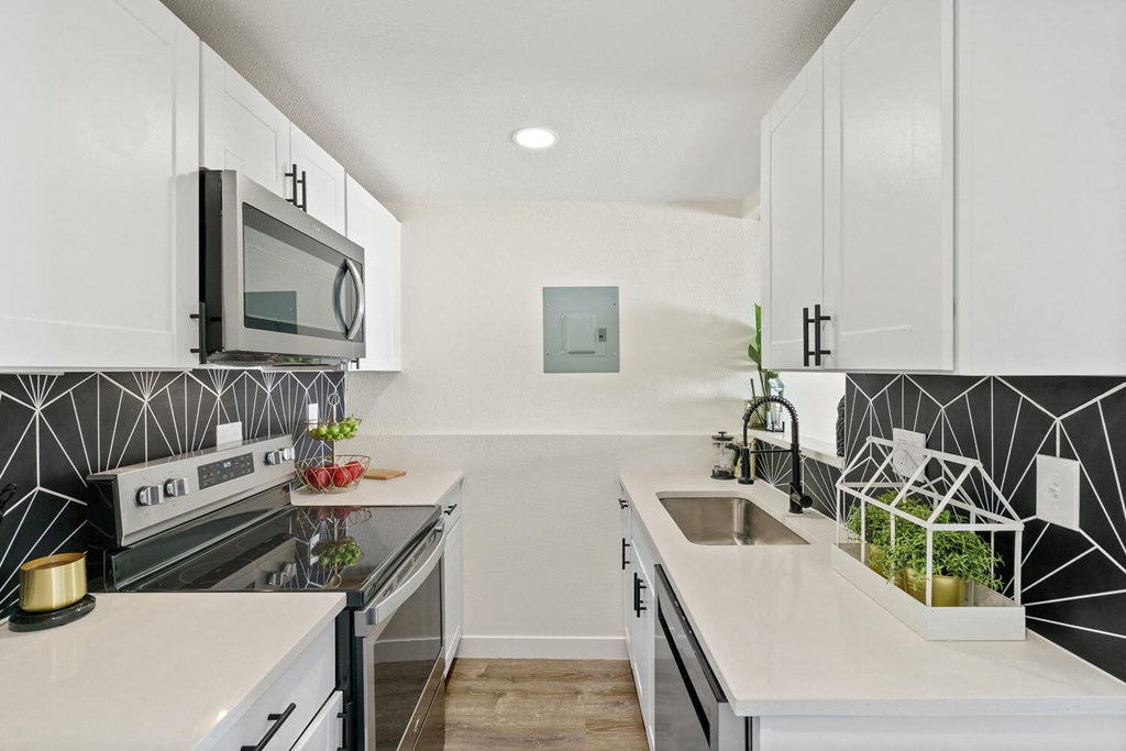 a kitchen with white cabinets and black and white tile