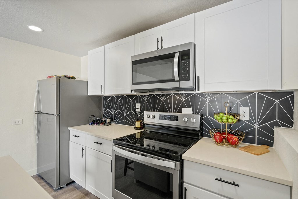 a kitchen with white cabinetry and black and white tile