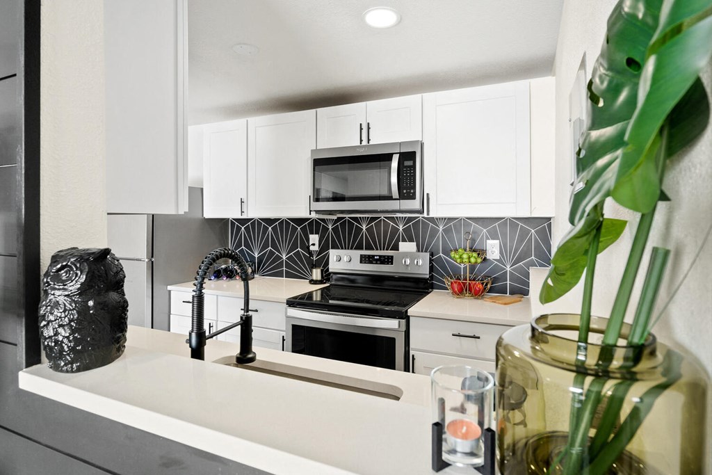 a kitchen with white cabinets and black appliances