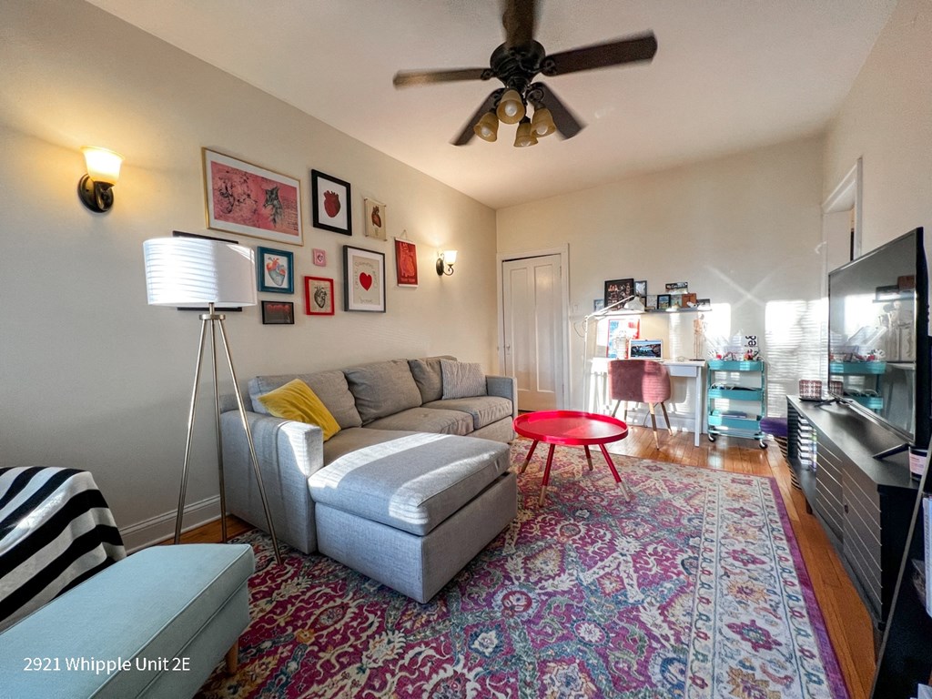 A living room with a grey couch and a red table.