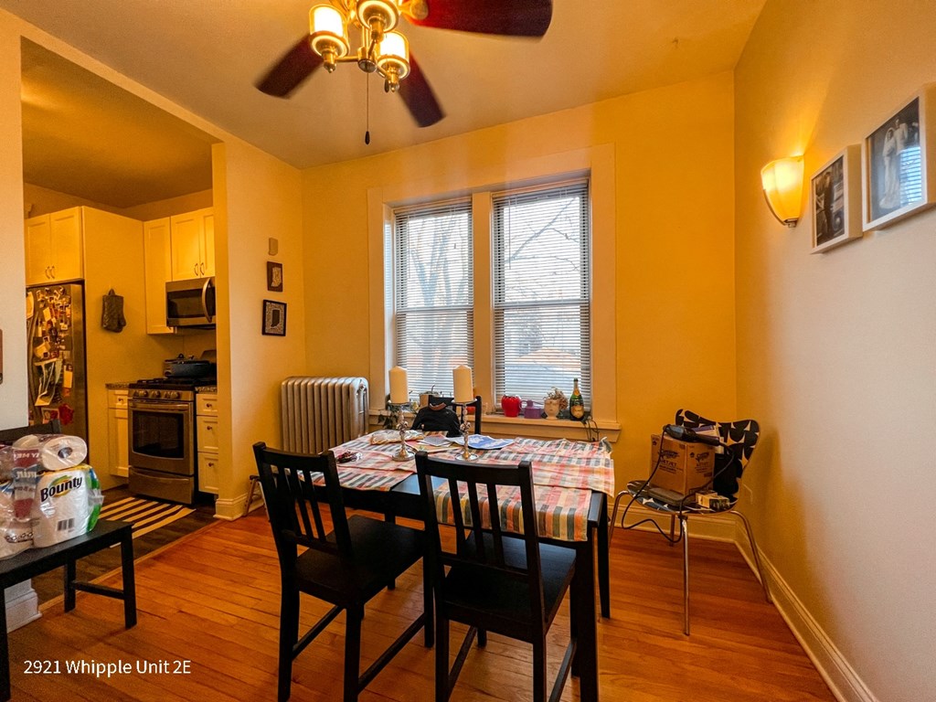 A dining room with a table set for two and a fan on the ceiling.