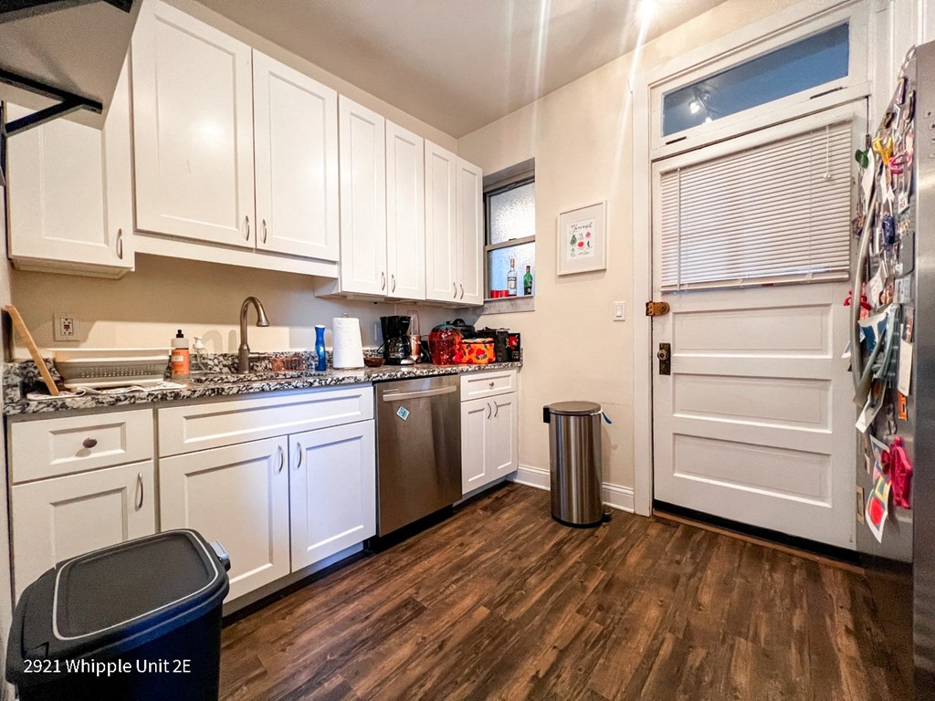 A kitchen with white cabinets and a wooden floor.