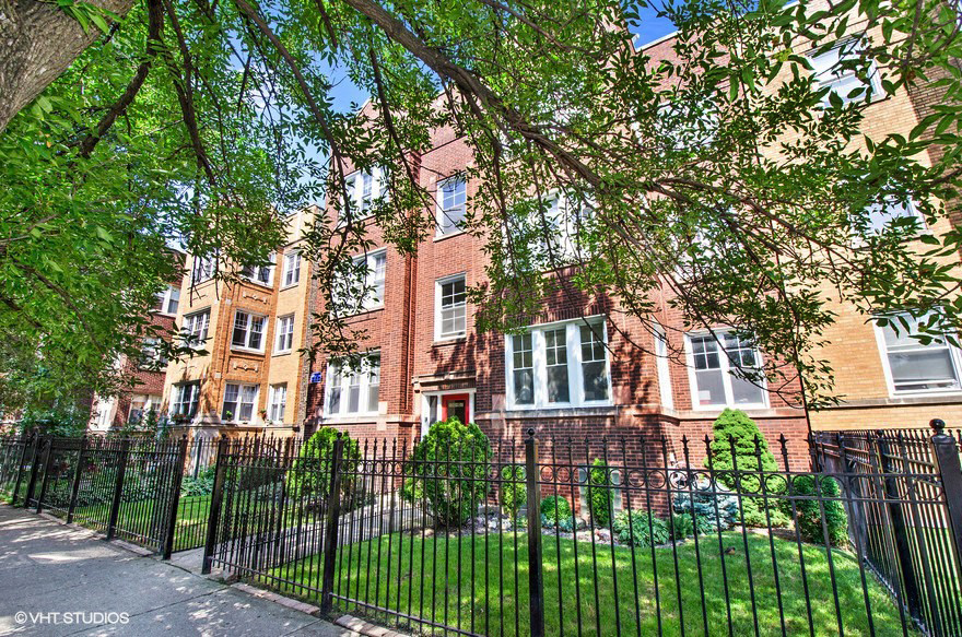 the front of a red brick house behind a black fence