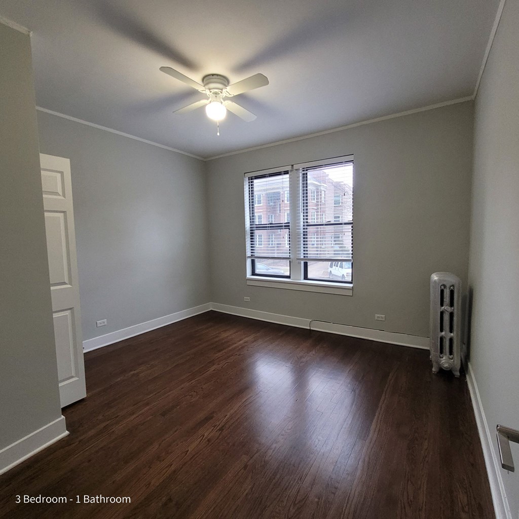 an empty living room with a ceiling fan and a window
