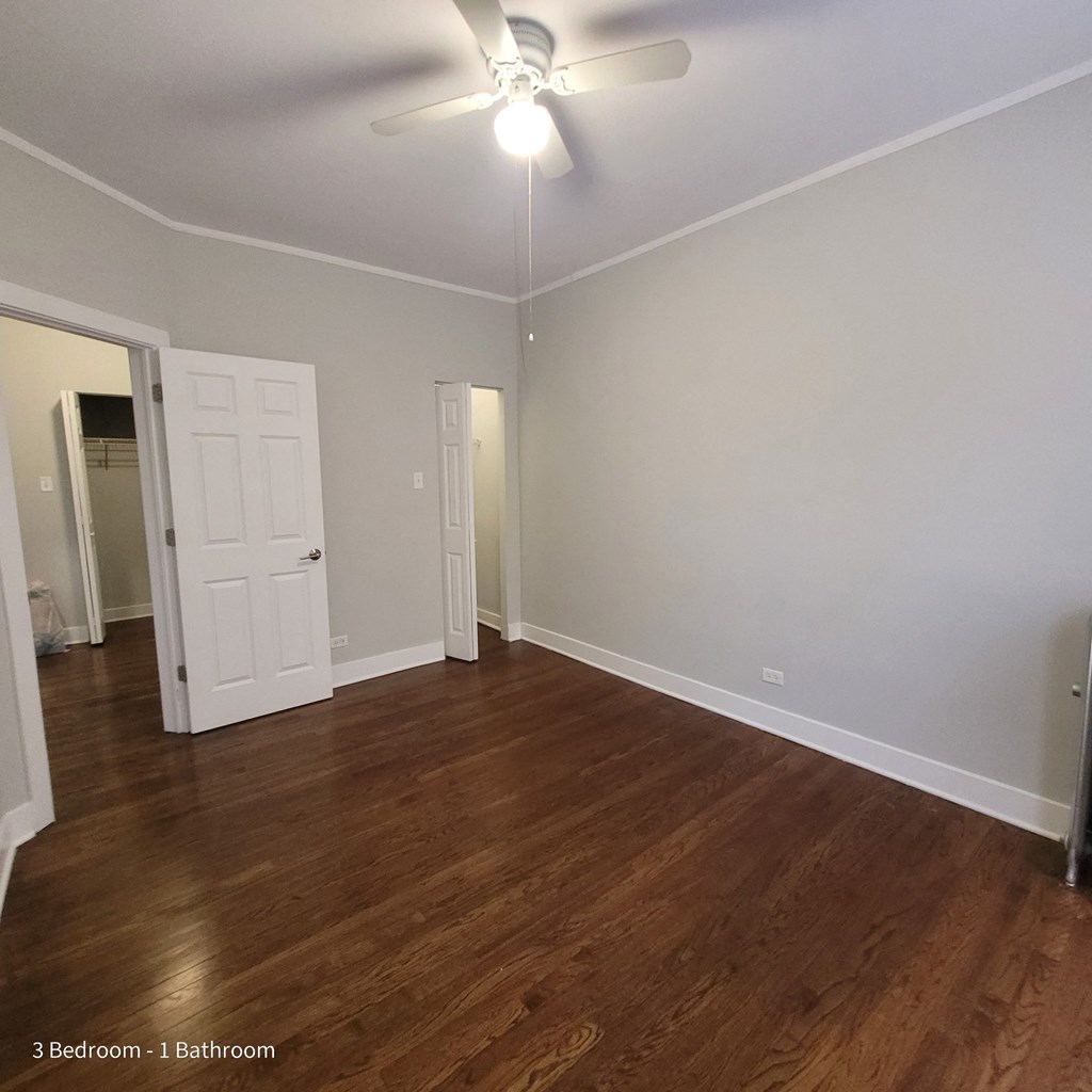 an empty living room with wood floors and a ceiling fan