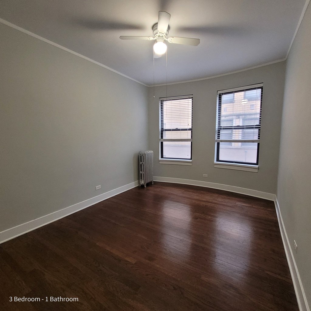 an empty living room with wood floors and a ceiling fan