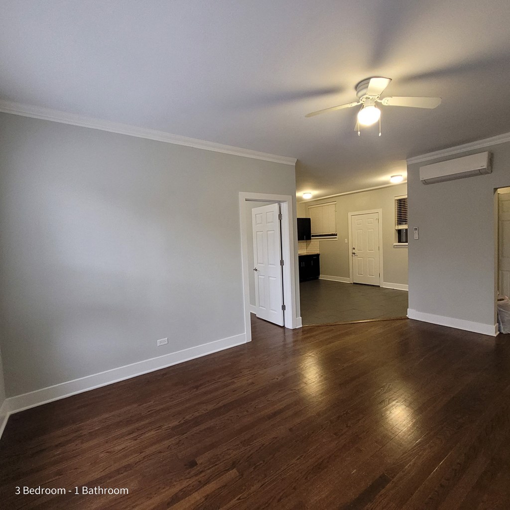 an empty living room with wood floors and a ceiling fan