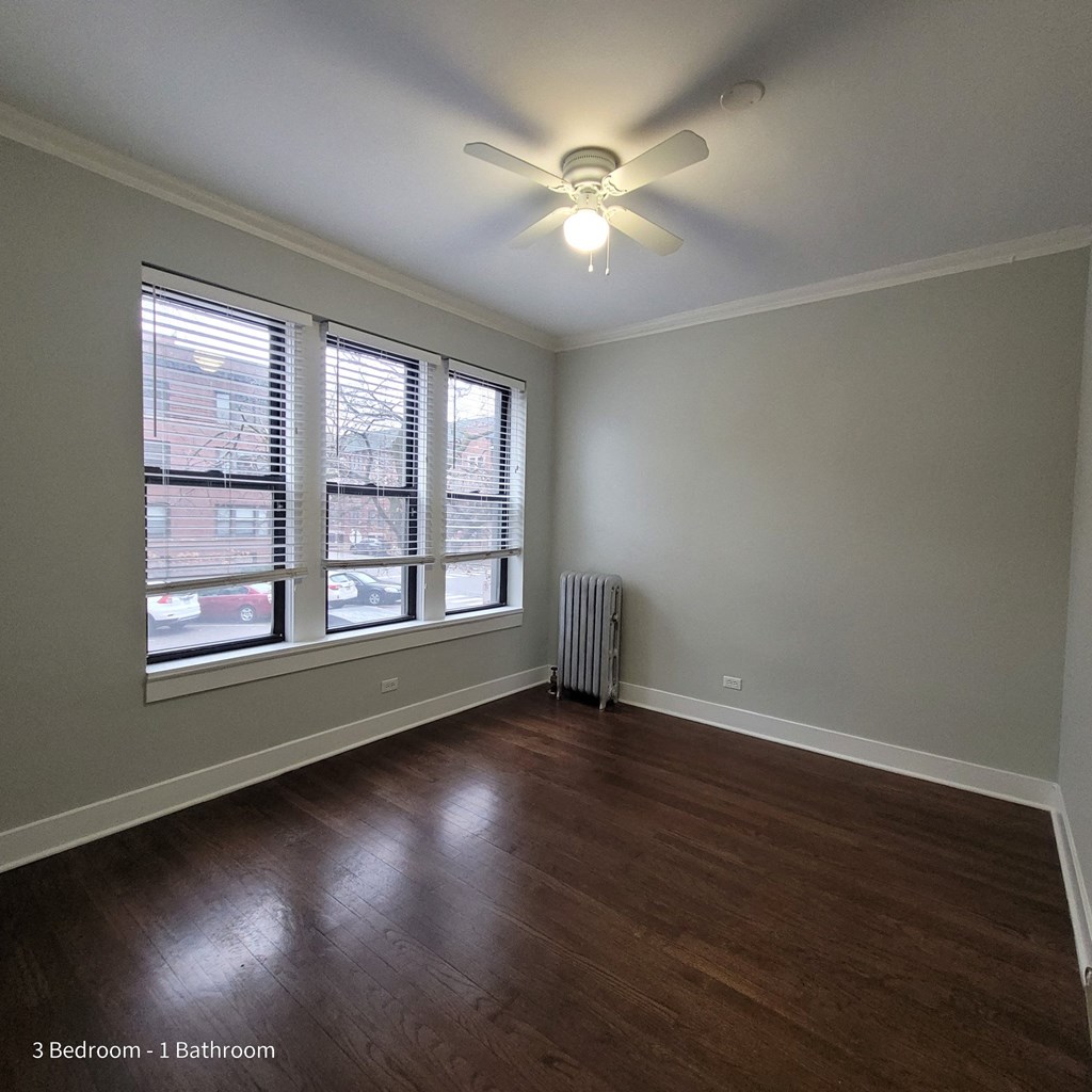 an empty living room with wood floors and a ceiling fan