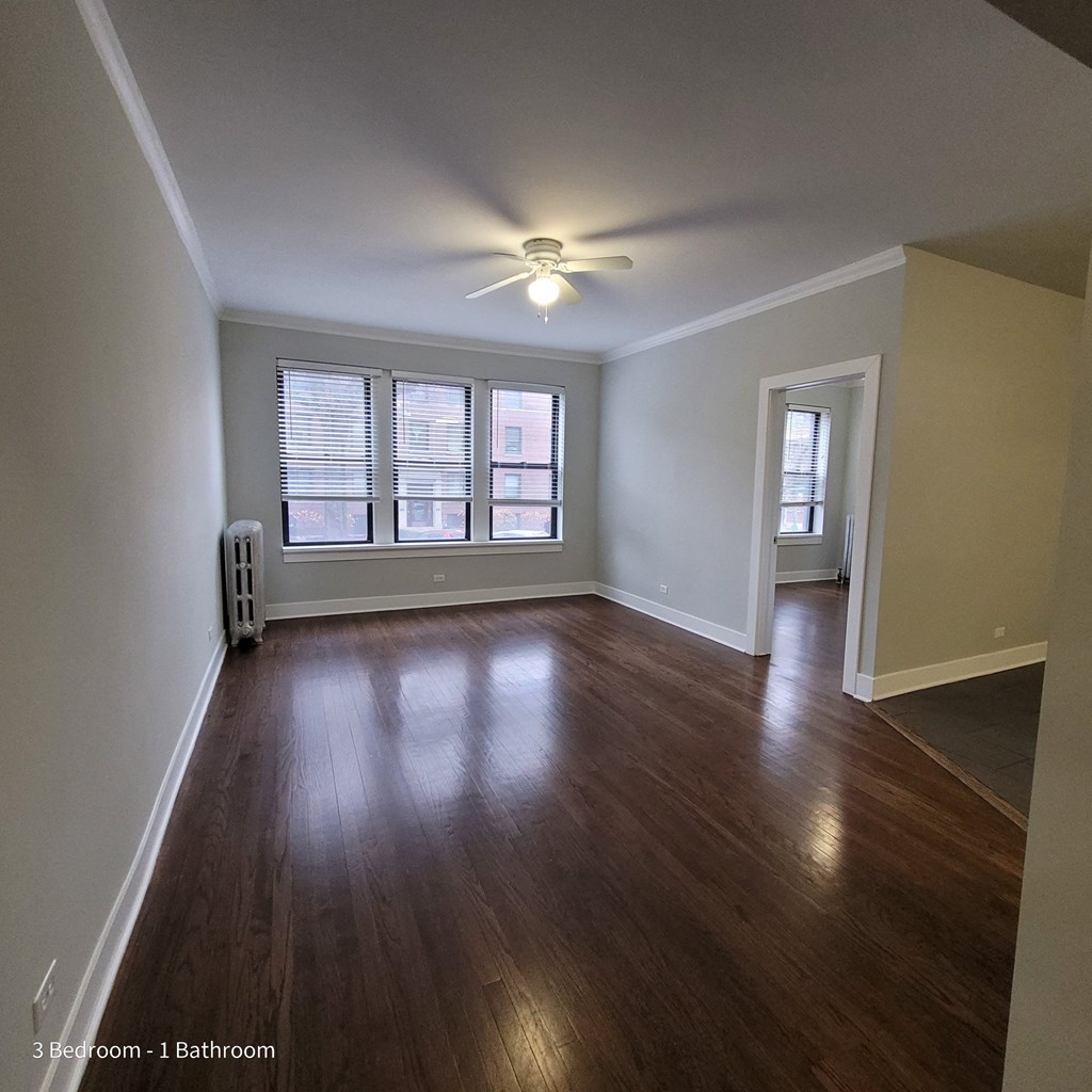 an empty living room with wood floors and a ceiling fan