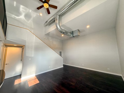 A room with a ceiling fan and a white wall.
