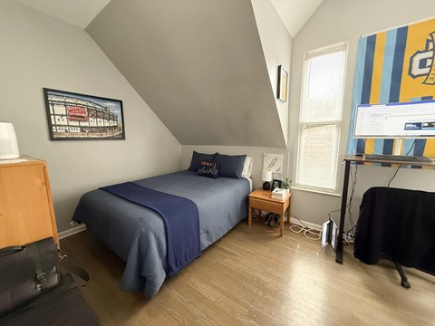 A bedroom with a bed, nightstand, and a painting on the wall.