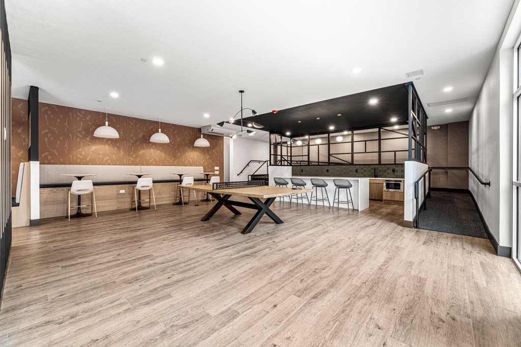 a common area with a table and chairs and a bar and a kitchen
