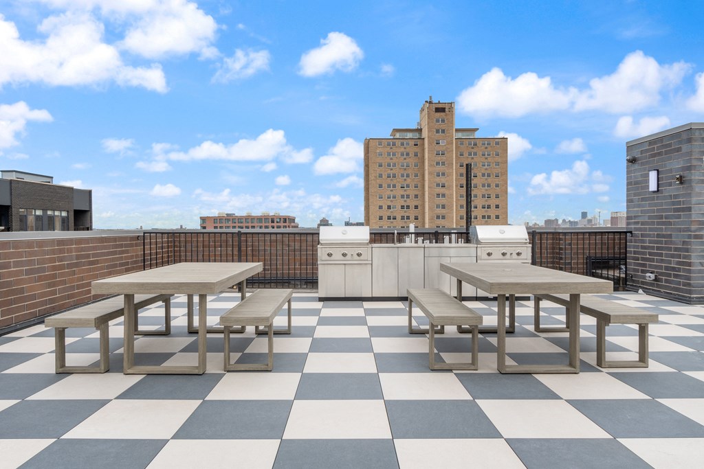 an outdoor kitchen and dining area on the roof of a building with a city skyline in the