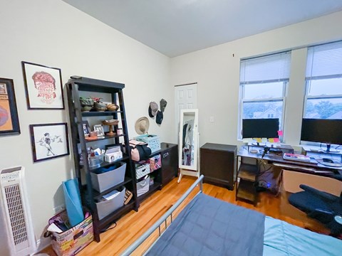 A room with a bed, desk, and bookshelf.