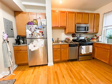 A kitchen with wooden cabinets and a refrigerator with many magnets on it.
