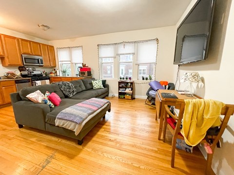 A living room with a grey couch and wooden floors.