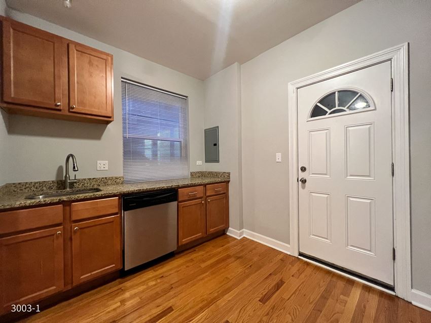 a kitchen with brown cabinets and a white door - Photo Gallery