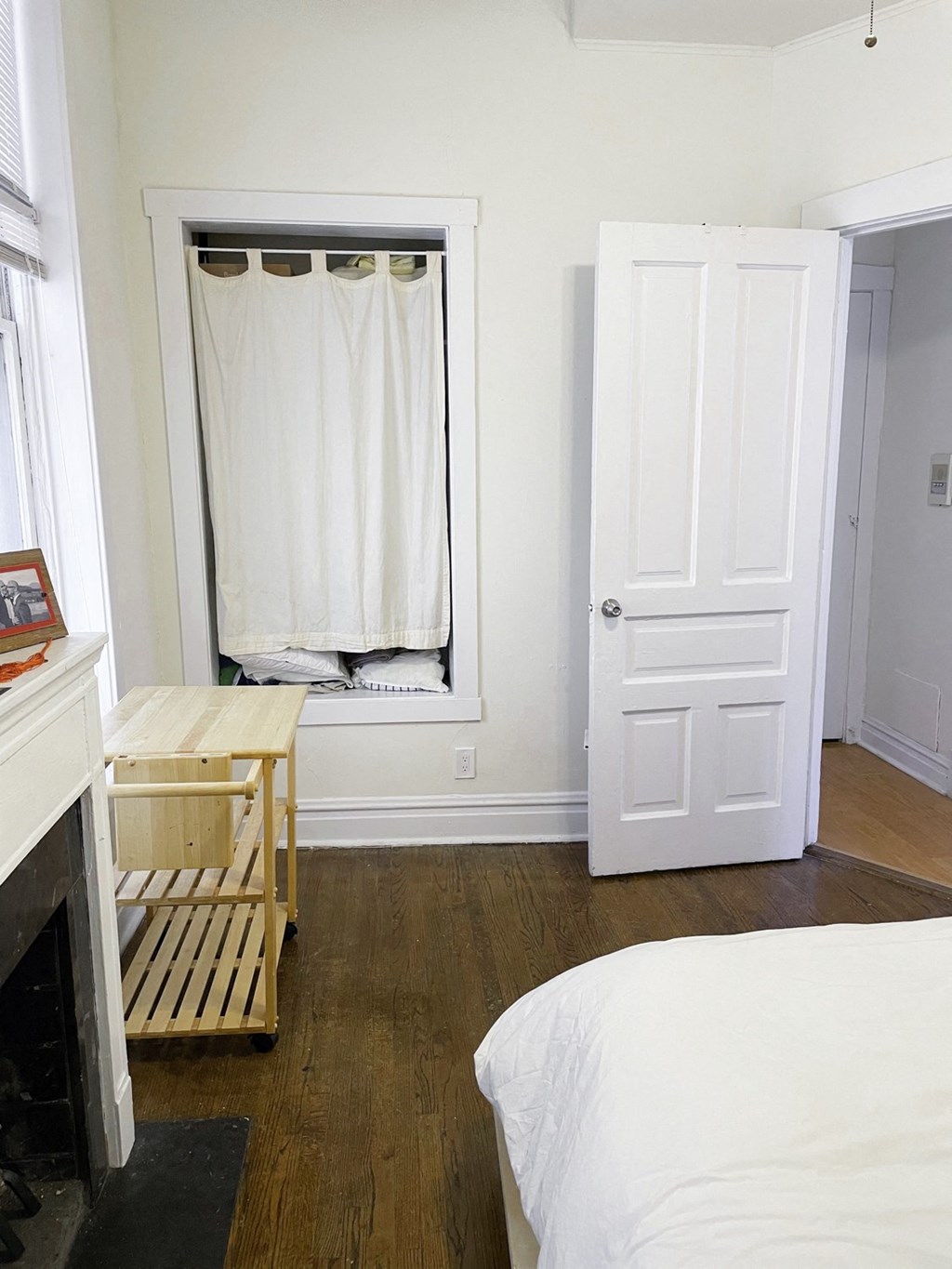 a small bedroom with a bed and a window with white curtains