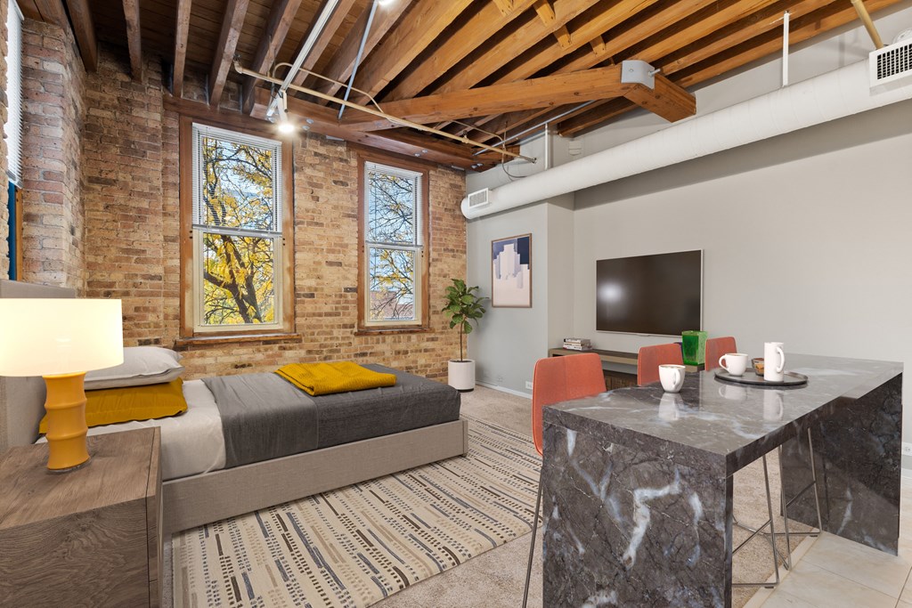 a living room with a bed and a desk and a tv