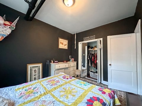 A bedroom with a bed, dresser, and mirror.