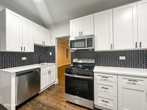 a kitchen with white cabinets and a stove and a microwave