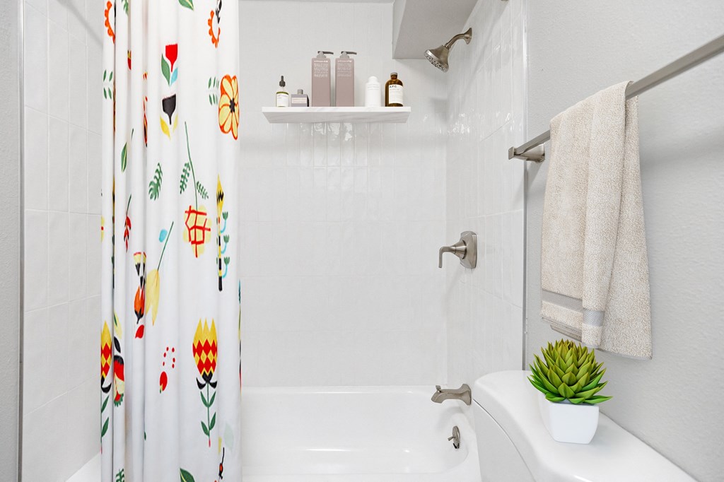 a white bathroom with a colorful shower curtain and a white toilet