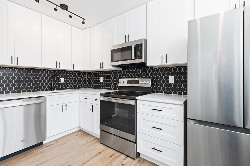 a kitchen with white cabinets and stainless steel appliances