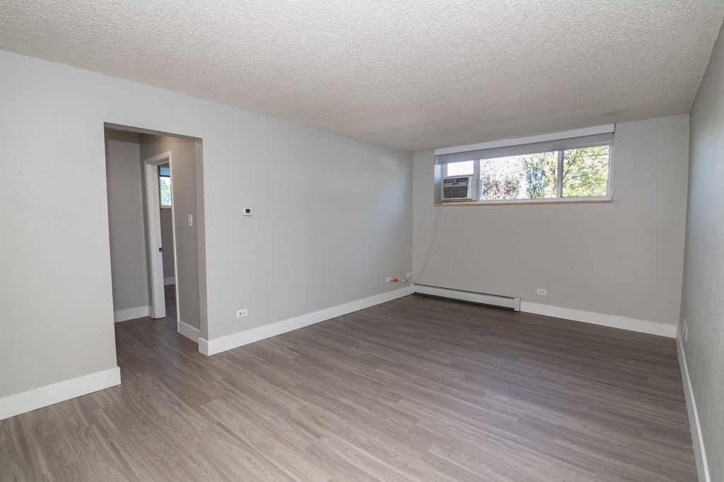 an empty living room with a window and hardwood floors