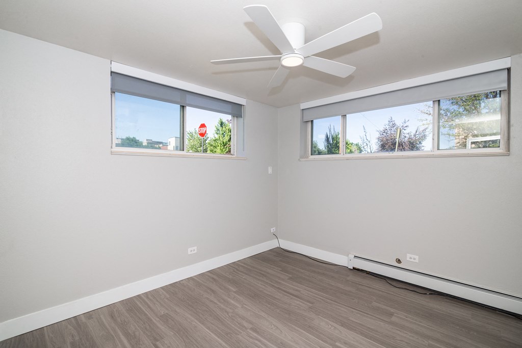 a bedroom with two windows and a ceiling fan