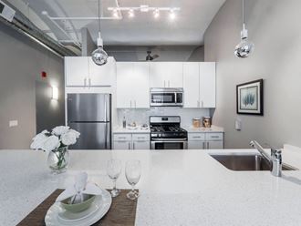 a white kitchen with stainless steel appliances and white counter tops