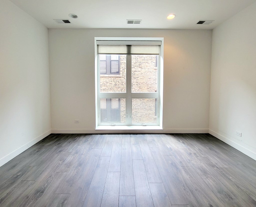 an empty living room with a large window and wood flooring