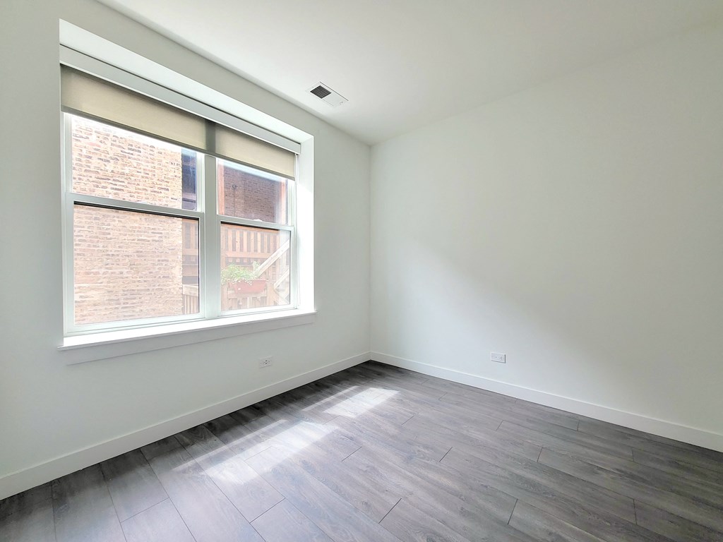 an empty room with wood floors and a window
