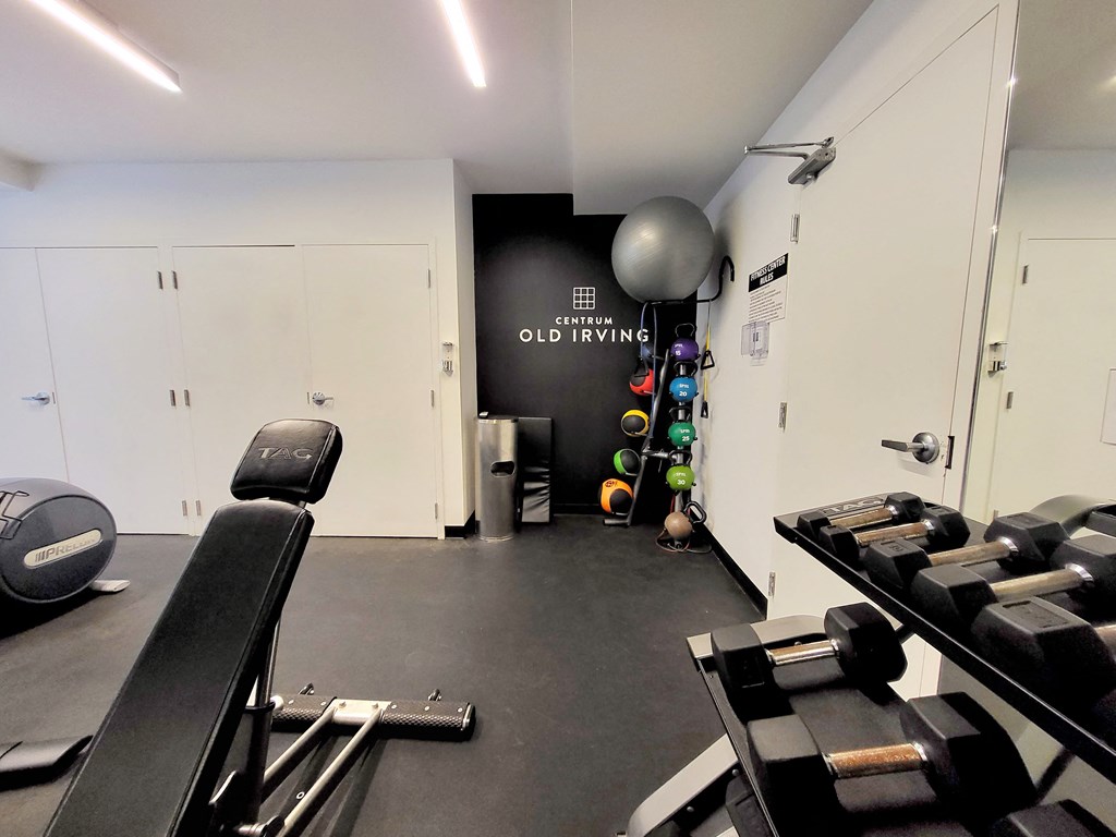 a gym with cardio machines and weights on the floor and a wall with a sign