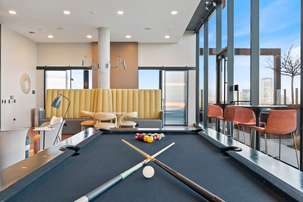 a resident lounge with a pool table and chairs and a table and large windows with views of Chicago