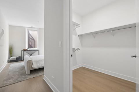 A white bedroom with a bed and a small table.