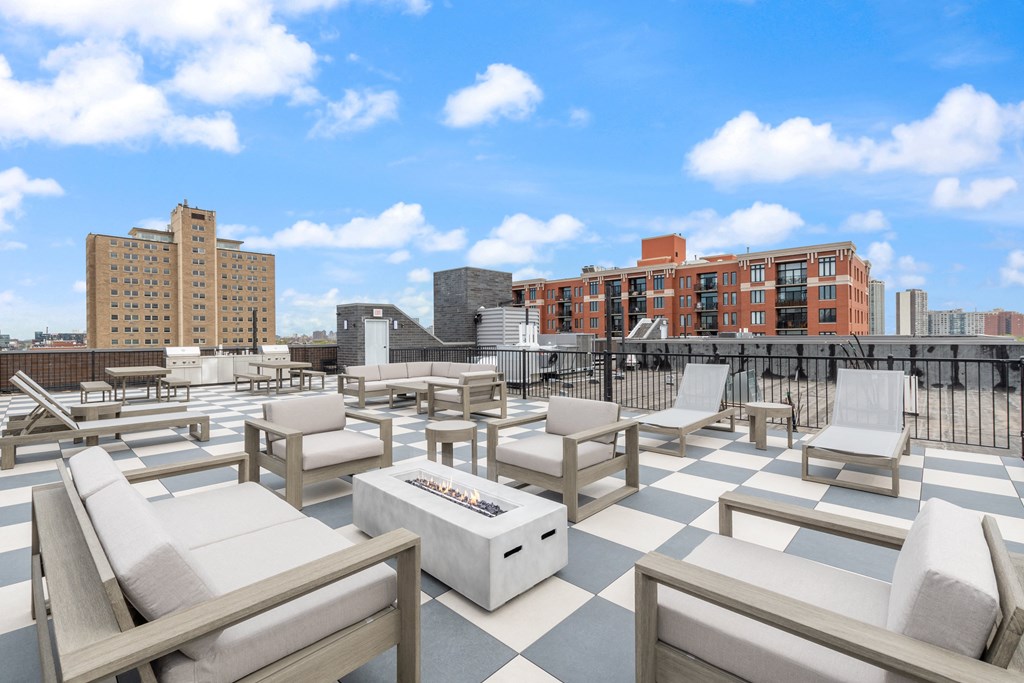 a roof deck with lounge chairs and a fire pit