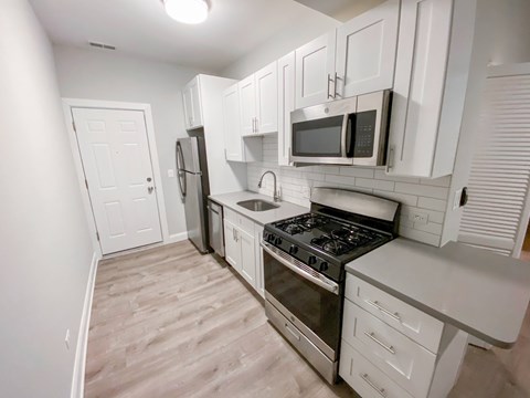 A kitchen with white cabinets and appliances.