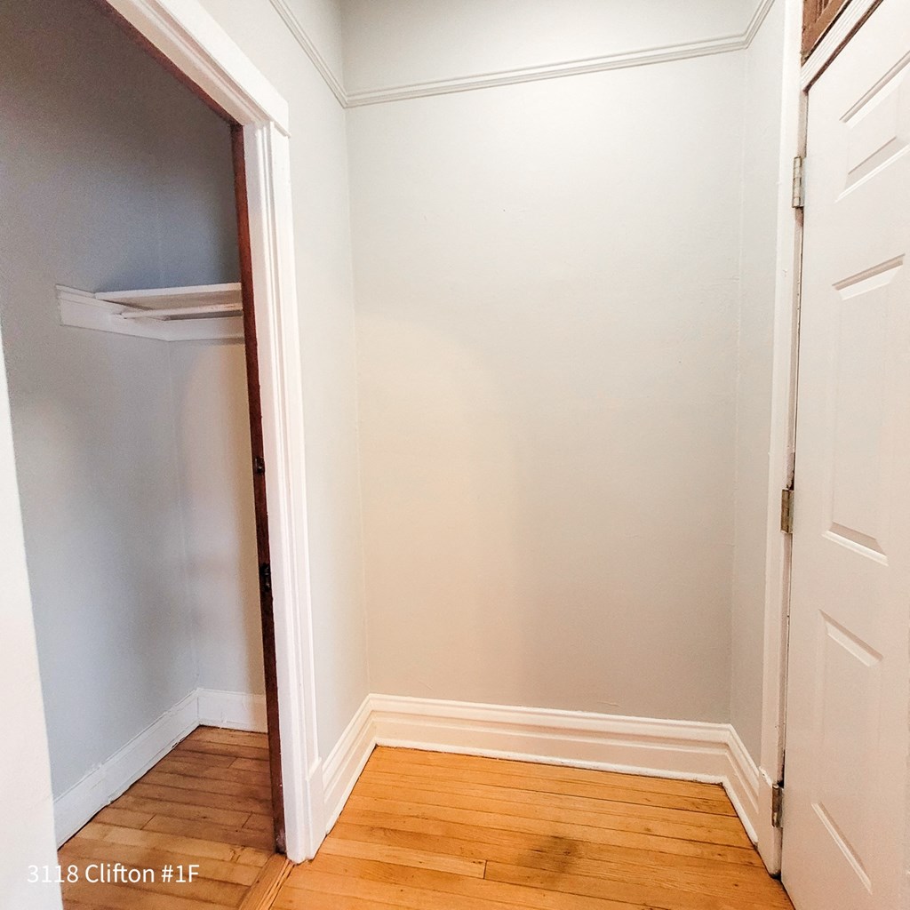 a closet in a small room with a wooden floor and a white door