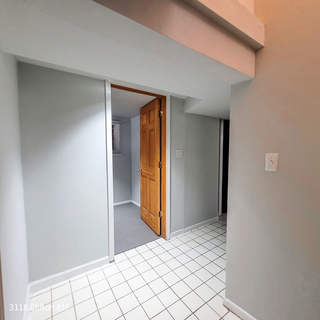 an empty hallway with a door to a closet and a tiled floor