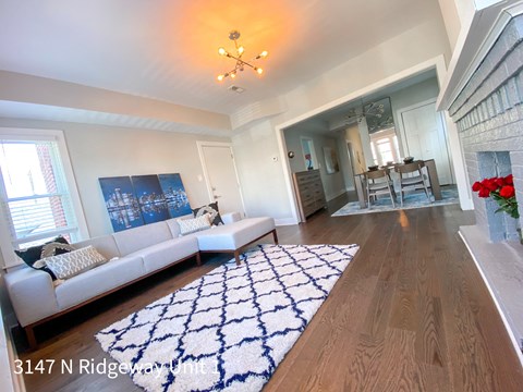 A living room with a white couch and a blue and white rug.