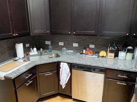 A kitchen with dark brown cabinets and a granite countertop.
