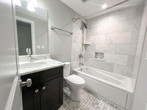 A white bathroom with a black vanity and a white toilet.