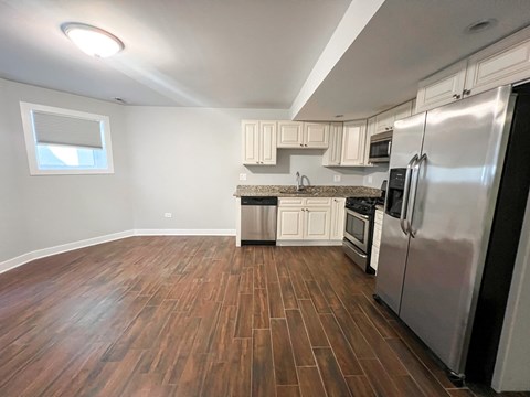 A kitchen with a stainless steel refrigerator and wooden flooring.